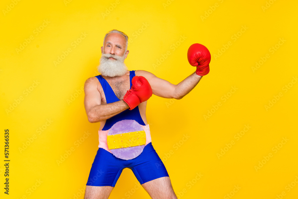Photo of handsome charismatic grandfather arms boxing gloves fighting isolated on yellow color background Photo of handsome charismatic grandfather arms boxing gloves fighting isolated on yellow color background
