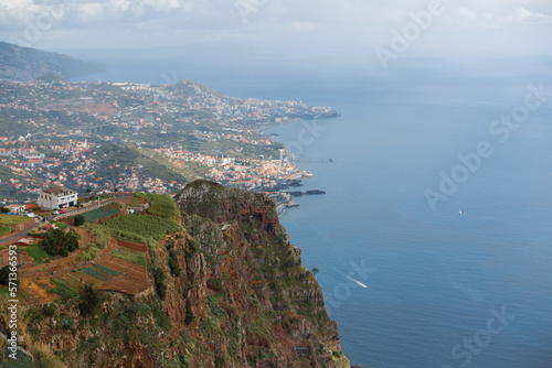 Amazing panoramic view of madeira island with mountains, city, houses, agro, ocean and boat. View from the observation deck Cabo Girão Skywalk