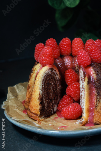 close up of home made marble cake with raspberries on top  dark grey background 