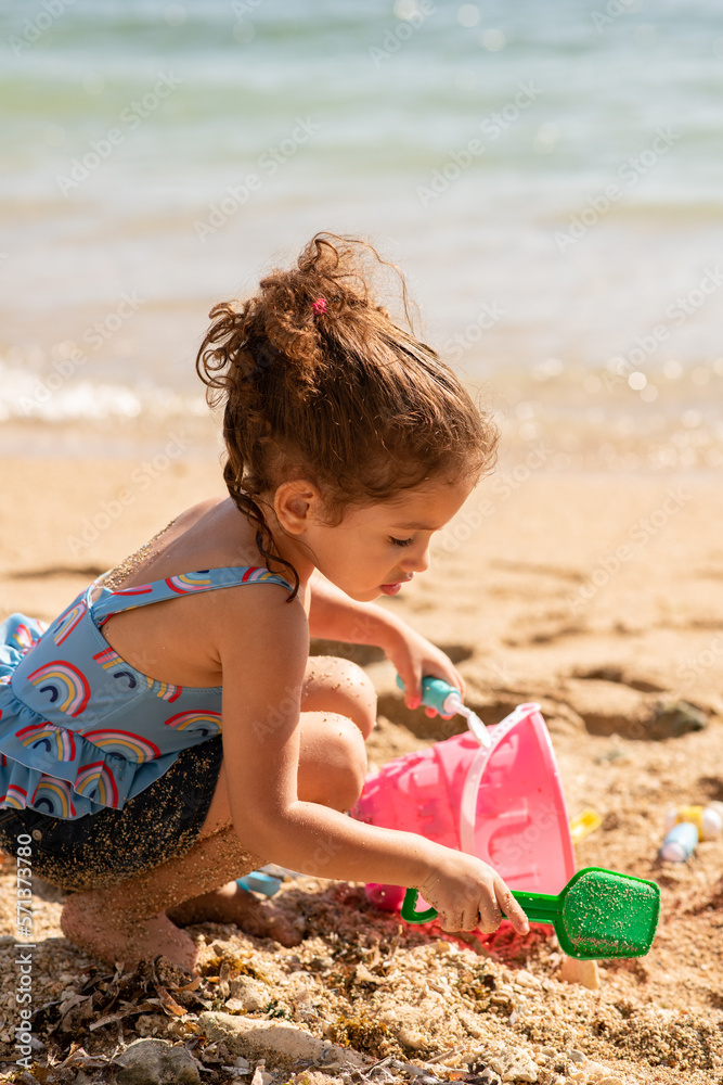 Adorable little girl playing with sand on the beach and having fun with toys of
beach and swimsuit on sunny day Adorable little girl playing with sand on the beach and having fun with toys of
beach and swimsuit on sunny day