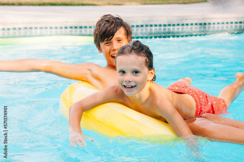 Two happy child having fun on summer pool. Boys playing at outdoor swimming pool