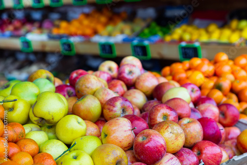 Bunches of various fresh fruits on shelves in salesroom of greengrocer.