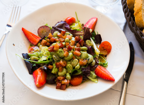 Colorful salad with candied beans, bacon marinated in soy-honey sauce, tomatoes, fruits and greens..