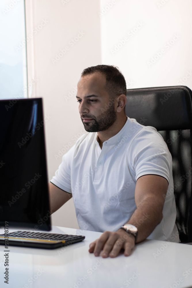 Naklejka premium Boy in white T-shirt working seriously at desk. Concept: office work