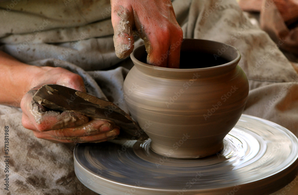 Pottery. Only the hands of a potter and a clay pot are in the frame.