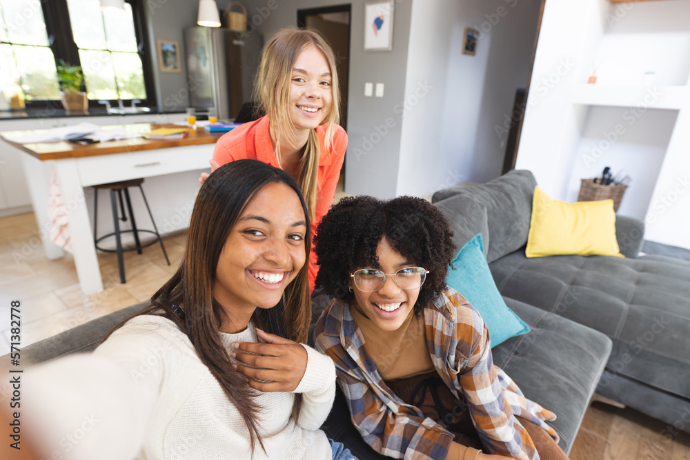 Portrait of happy diverse teenage female friends sitting on couch taking selfie Portrait of happy diverse teenage female friends sitting on couch taking selfie