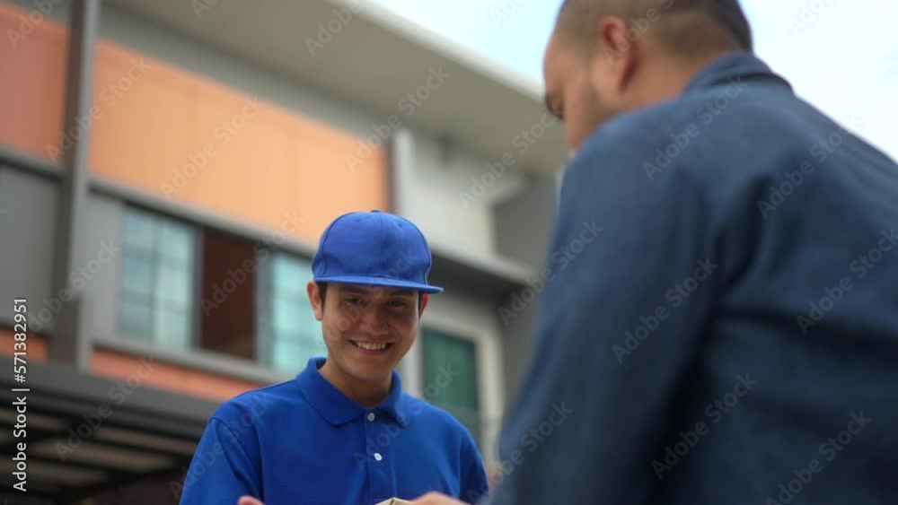 Blue uniform delivery handsome man send parcel to customer front of the house with good service from shopping online. Courier man delivering a cardboard box postal package to destination. Blue uniform delivery handsome man send parcel to customer front of the house with good service from shopping online. Courier man delivering a cardboard box postal package to destination.