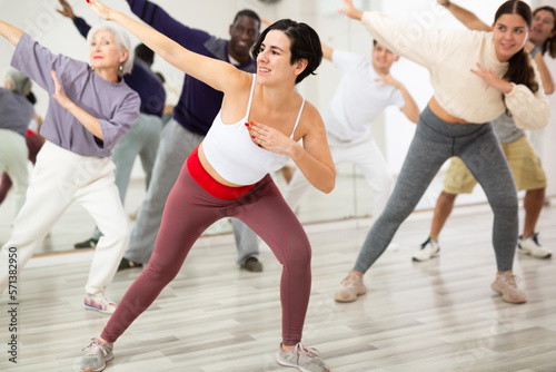 Group of adult people, engaged in the dance school, practices dance aerobics in class