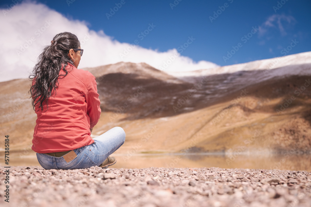 Naklejka premium mujer latina contemplando laguna entre montañas nevadas de los Andes
