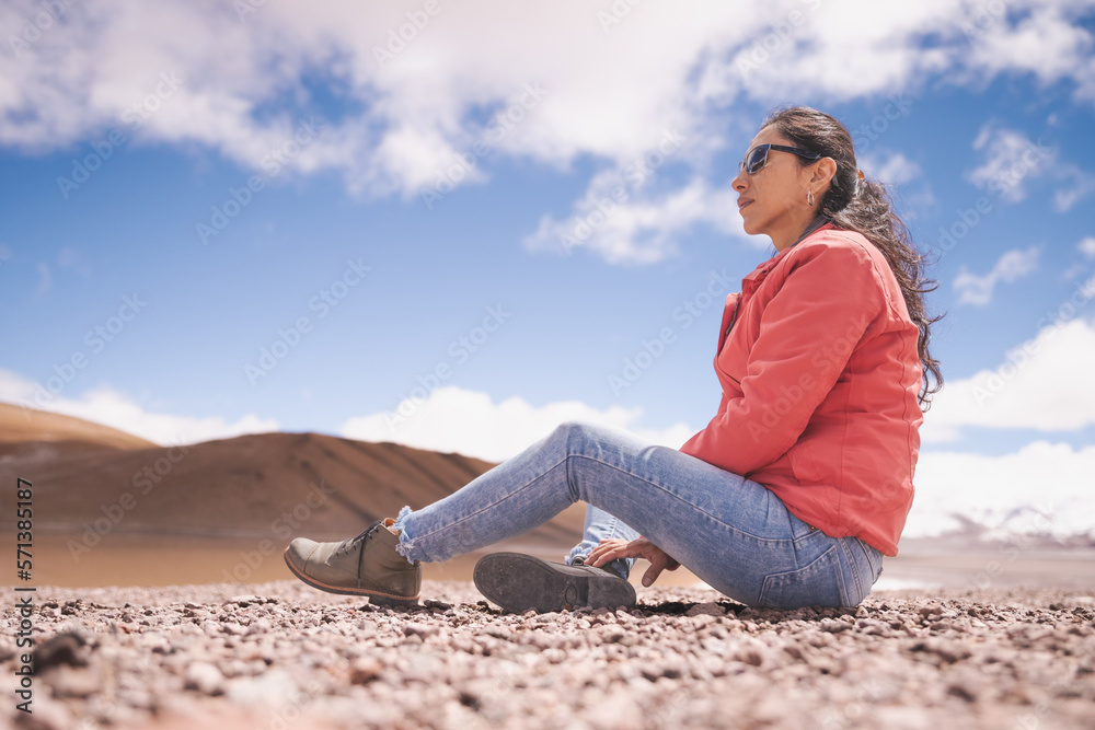 mujer latina contemplando laguna entre montañas nevadas de los Andes