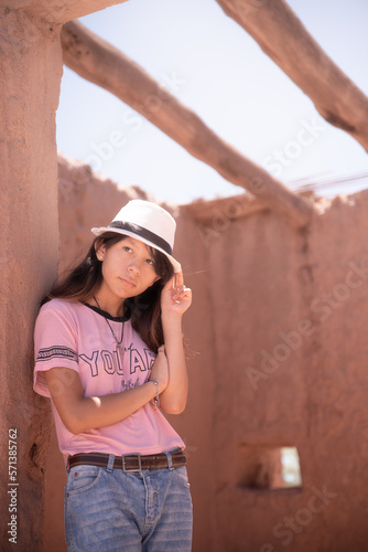 mujer adolescente con sombrero en antigua casa de adobe, Catamarca Argentina