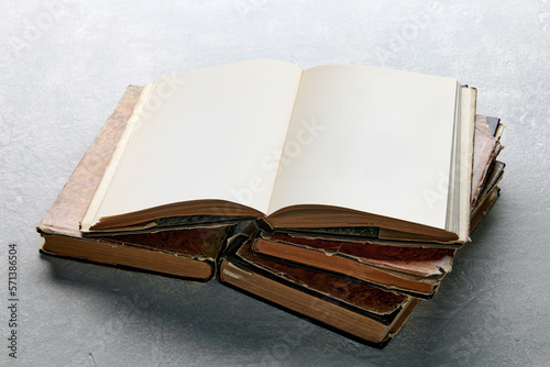 Open vintage book or notebook in a super jacket on a stack of old shabby books on a light concrete table