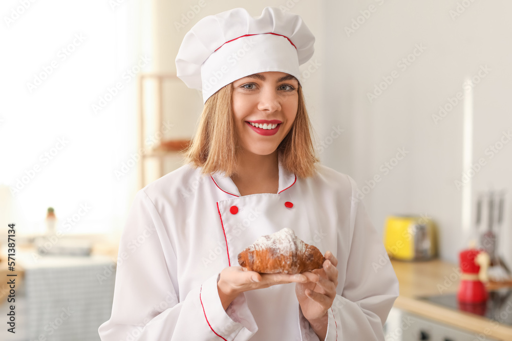 Female baker with tasty croissant in kitchen Female baker with tasty croissant in kitchen