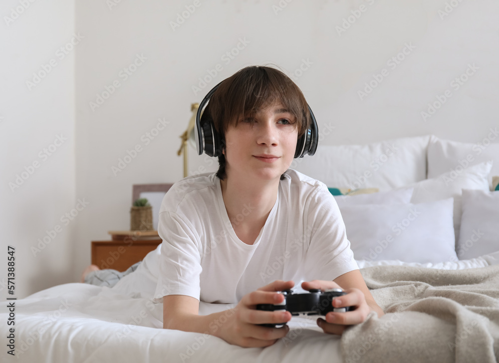 Teenage boy with headphones playing video game in bedroom Teenage boy with headphones playing video game in bedroom