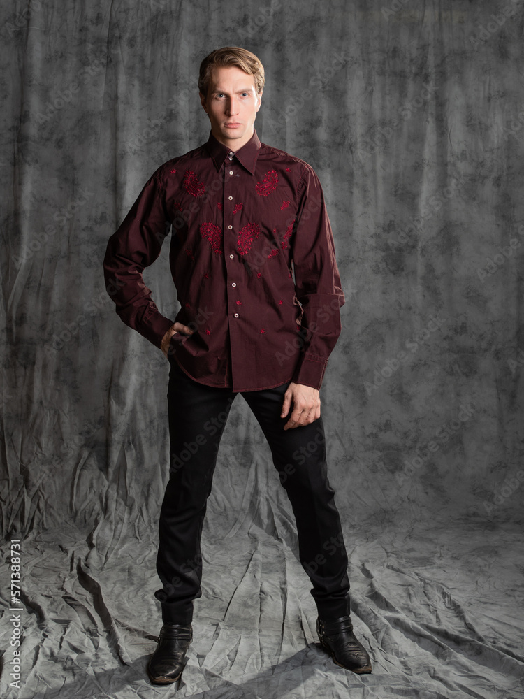 an attractive man in an elegant suit, burgundy shirt with embroidery. Photo in the studio on a gray background an attractive man in an elegant suit, burgundy shirt with embroidery. Photo in the studio on a gray background