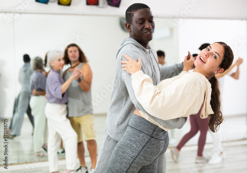 Adult couples of dancers, engaged in a dance studio, studying salsa in lesson