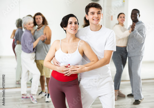 Smiling young Hispanic woman and handsome guy attending group choreography class, learning modern dynamic pair dances. Concept of active lifestyle..
