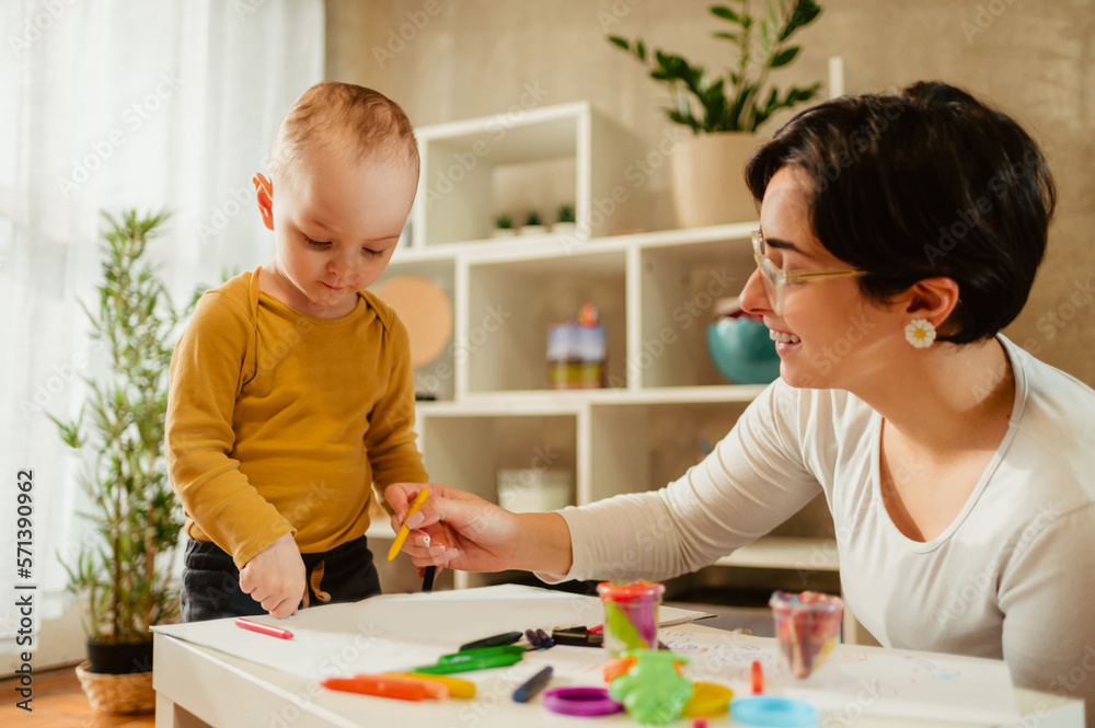 Fototapeta premium Mother and son drawing with crayons at home and having education