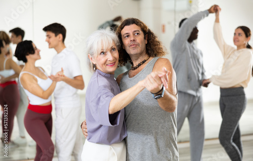 Dancing positive couple learns a slow foxtrot in a lesson in a dance studio
