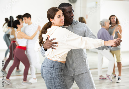 African man and caucasian young woman learning paired latin dances