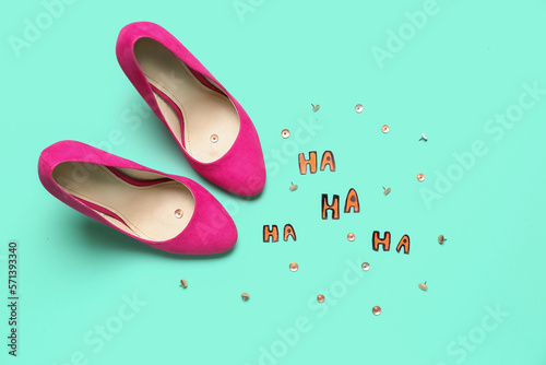 Composition with pair of stylish high-heeled shoes, paper words HA and pins on color background. April Fool's Day celebration