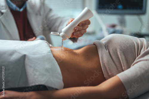 Selective focus on ultrasound scanner device in the hand of a professional doctor examining his patient doing abdominal ultrasound scanning sonogram sonography sonographer early pregnancy