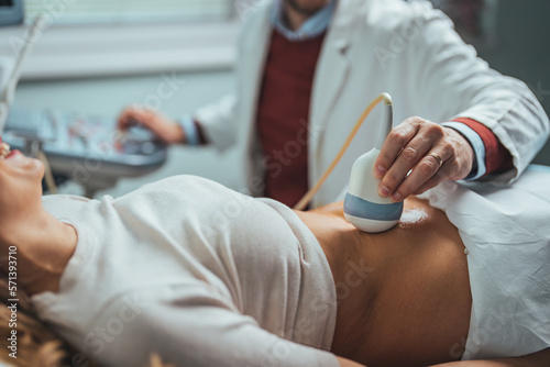 Gynecologist doctor does ultrasound  sonogram procedure to a pregnant woman. Doctor makes the patient women abdominal ultrasound. Ultrasound Scanner in the hands of a doctor. Diagnostics. Sonography