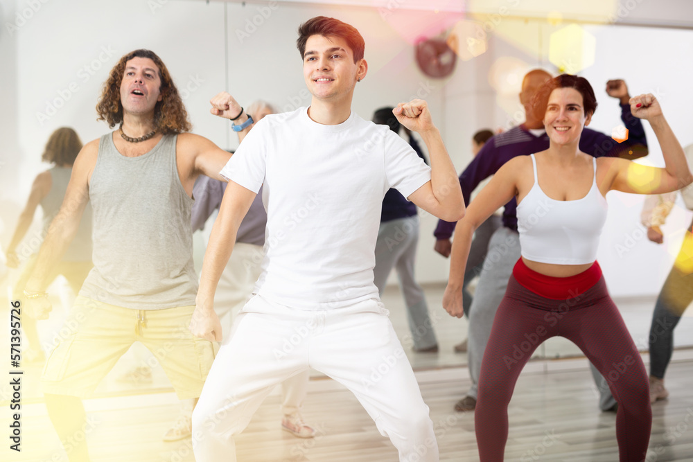 Fototapeta premium Smiling dark-haired young guy attending group choreography class, learning modern dynamic dances. Concept of active lifestyle ..