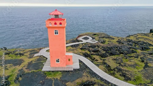 Bright red orange Svortuloft Lighthouse and stormy sea behind him on a cold autumn day photo