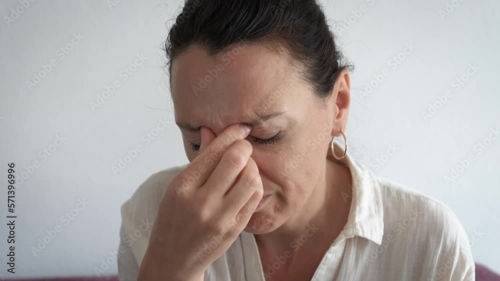 Sick female massaging nose indoor. A view of sad female with head ache massaging her nose to reduce the pain in the room. Sick female massaging nose indoor. A view of sad female with head ache massaging her nose to reduce the pain in the room.