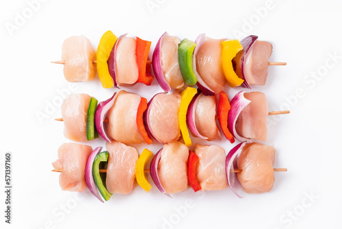 Raw chicken skewers with vegetables, peppers, onions, on a white background.Uncooked mixed meat skewer with peppers.Skewers with pieces of raw meat, red, yellow and green pepper.Top view. photo