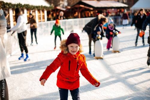 A young girl is skating on an outdoor rink. Girl in a red jacket. happy childhood