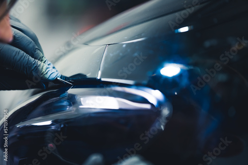 Precision cutting the darkening film on a headlight in car tuning garage. High quality photo