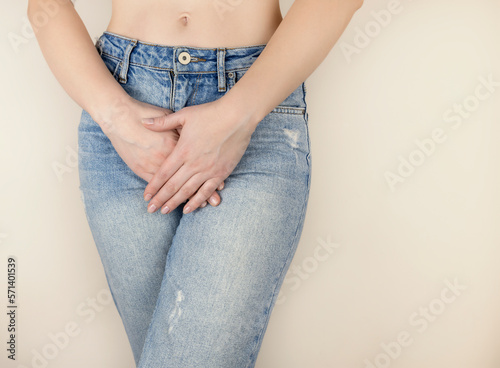 Close-up of a woman holding her hands below her stomach. A medical or gynecological problem. Women's days, stomach ache.