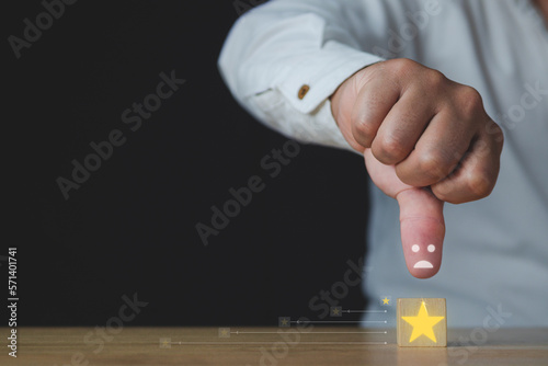 The man shows thumbs down or dislike. That is an evaluation. A cube has a star that means a bad job and service for customer review. Close up shot with copy space. Isolated on black background.