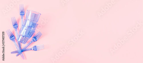 Three blue plastic transparent glasses and five forks on a pink background.