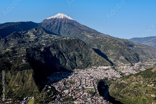 Aerial view of the Tungurahua volcano with a in snow covered top and the village Banos de Agua Santa in front of it photo