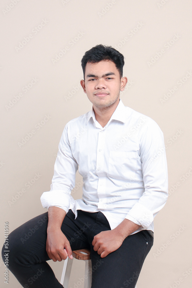 Asian man sitting on chair isolated on cream background Asian man sitting on chair isolated on cream background