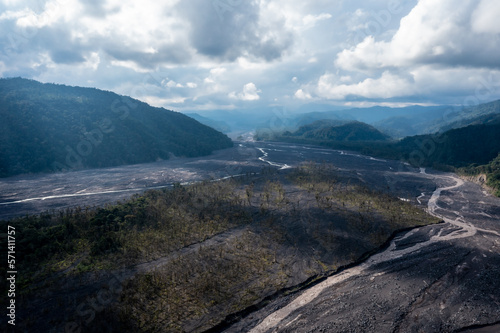 A meandering river has worn out a broad riverbed in the foothills of the Andes of Ecuador, trees are growing in the dirty river Upano due to the ashes of the volcano Sangay