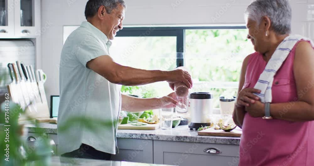 Happy senior biracial couple preparing healthy drink in kitchen Happy senior biracial couple preparing healthy drink in kitchen