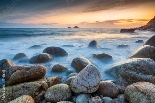 Sunset at Porth Nanven in Cornwall, with the Brison Rocks in the distance, the smoke like sea created by a long exposure. photo