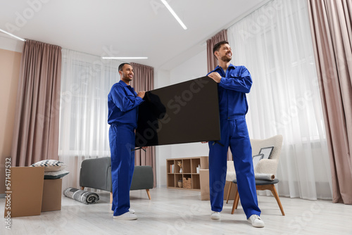 Male movers carrying plasma TV in new house © New Africa