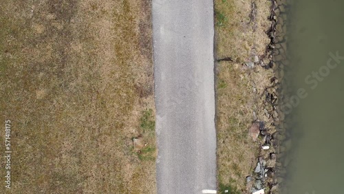 This is a short shot of a black dressed runner, which is filmed above him. Here is a piece of a river with a stonebeach in the autumn afternoon. The darkgreen and brown grass gives a flair of fall. photo