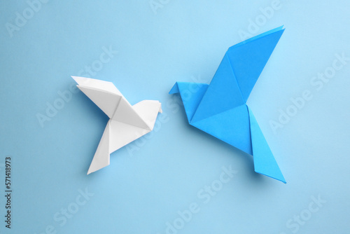 Origami art. Colorful handmade paper birds on light blue background, flat lay