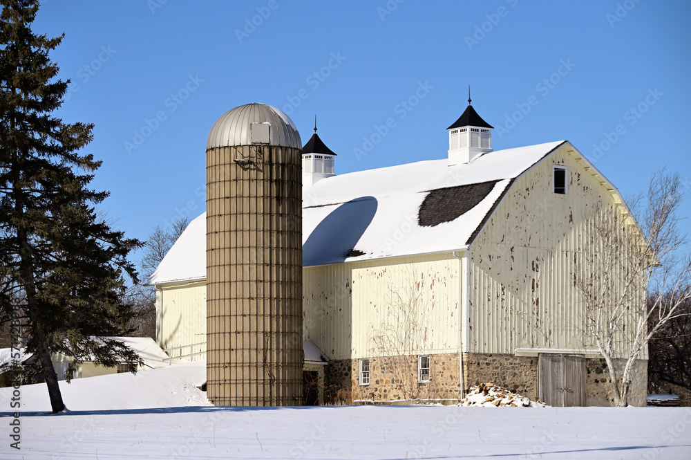 A barn and its attached silo stand out from the snow on a bright winter day in northeastern Illinois. Winters can be harsh in the Midwestern US but even on a bright sunny day all activity ceases. A barn and its attached silo stand out from the snow on a bright winter day in northeastern Illinois. Winters can be harsh in the Midwestern US but even on a bright sunny day all activity ceases.