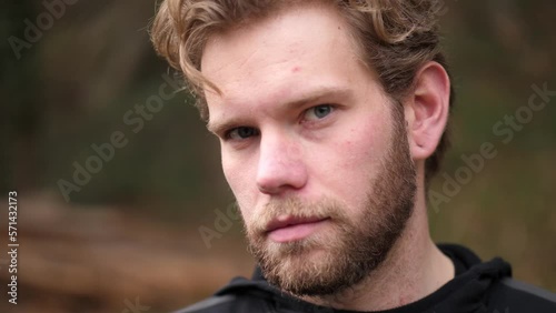 a slow motion shot of a serious looking man. He is wearing a brown colored beard and have dark blue eyes. With a wink he enchants all viewers. photo