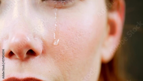 The video footage that shows the moment when tears flow down the face of a crying woman in a macro shot.