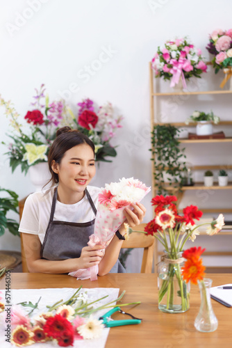 Flower shop concept, Female florist smile and holds colorful flower bouquet with paper and ribbon