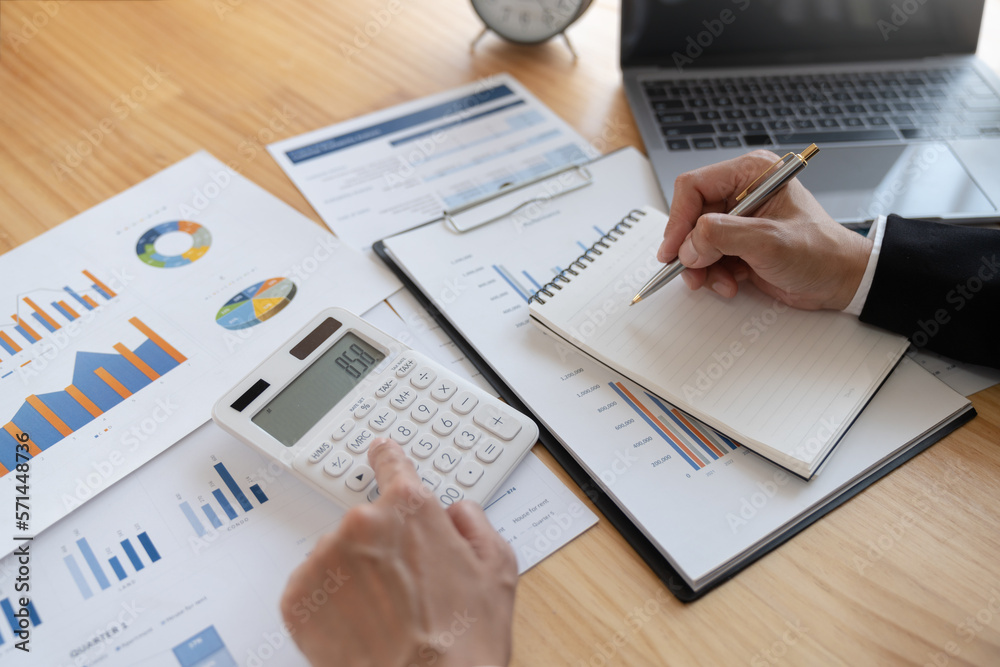 Asian business woman Calculate earnings with a calculator. Taking notes in a notebook for financial reporting or profits. Income tax. Management concept. Accounting and finance. Asian business woman Calculate earnings with a calculator. Taking notes in a notebook for financial reporting or profits. Income tax. Management concept. Accounting and finance.