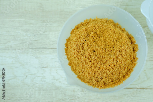 Brown sugar from natural cane juice on a white bowl, flat layout, copy space